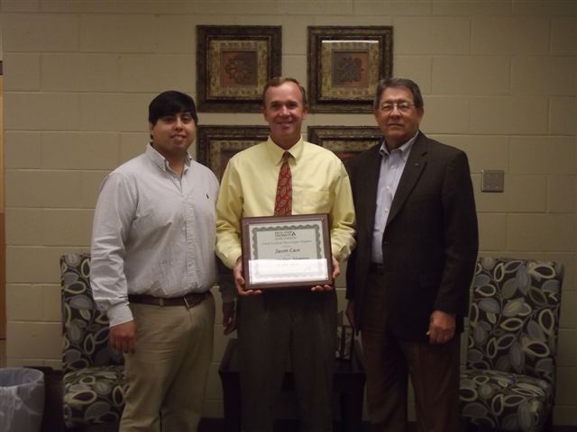 PHOTO: Luis Ybarra ‘07, chapter president, and Bradley Smith ‘71, past president, presenting a plaque to Jason Case ’86 in Brookhaven.  